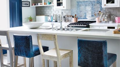 White kitchen with island and mismatched blue and wooden bar stools