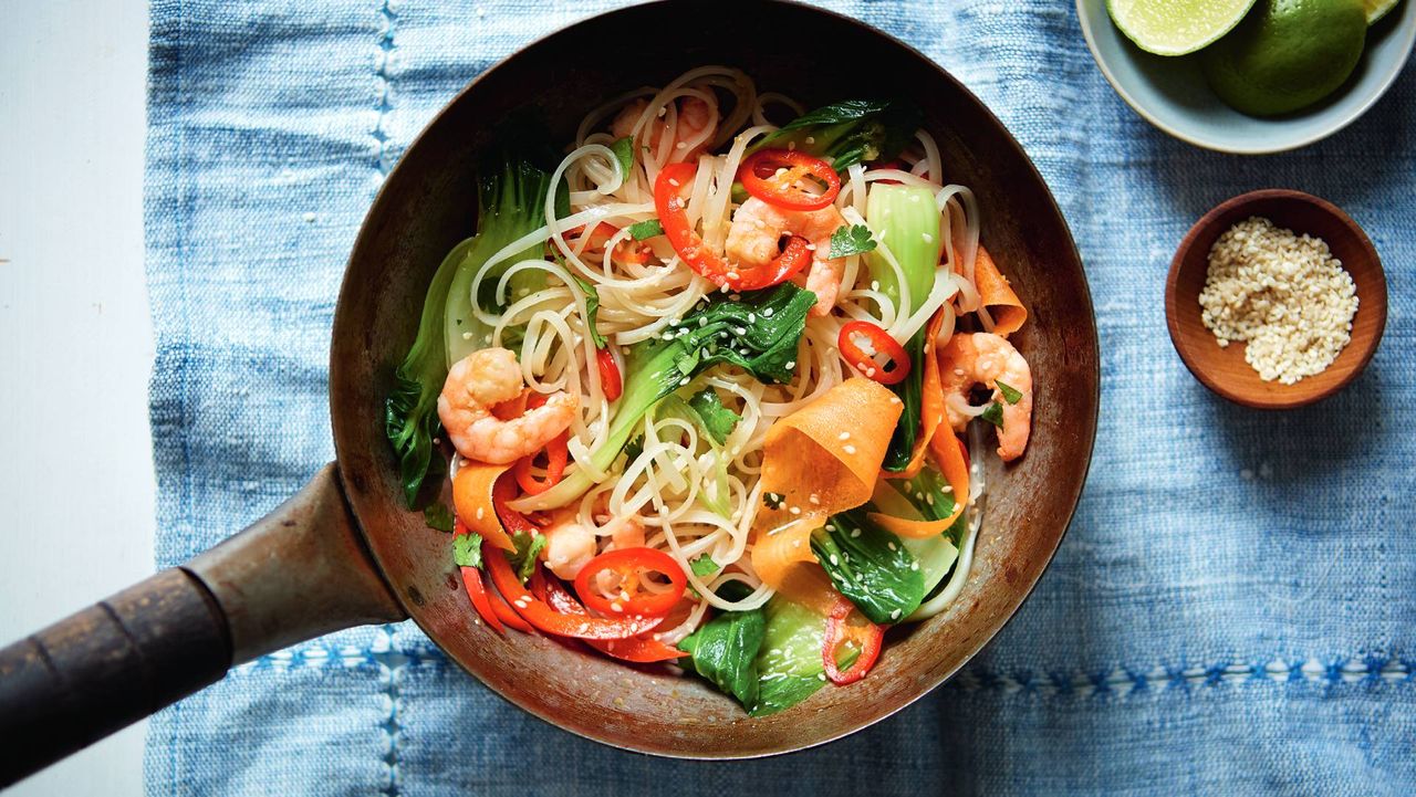 Small frying pan with stir fry ingredients and a pinch pot of seasoning ona blue cloth