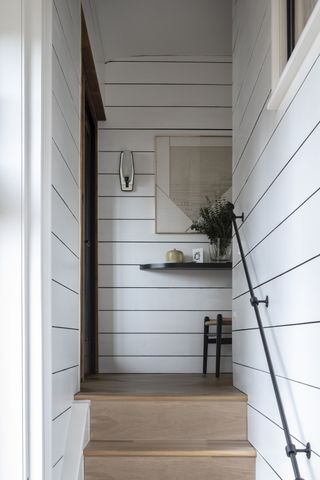 white hallway and stairs with white shiplap walls