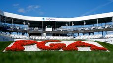 A PGA logo in red flowers in front of a Cognizant grandstand