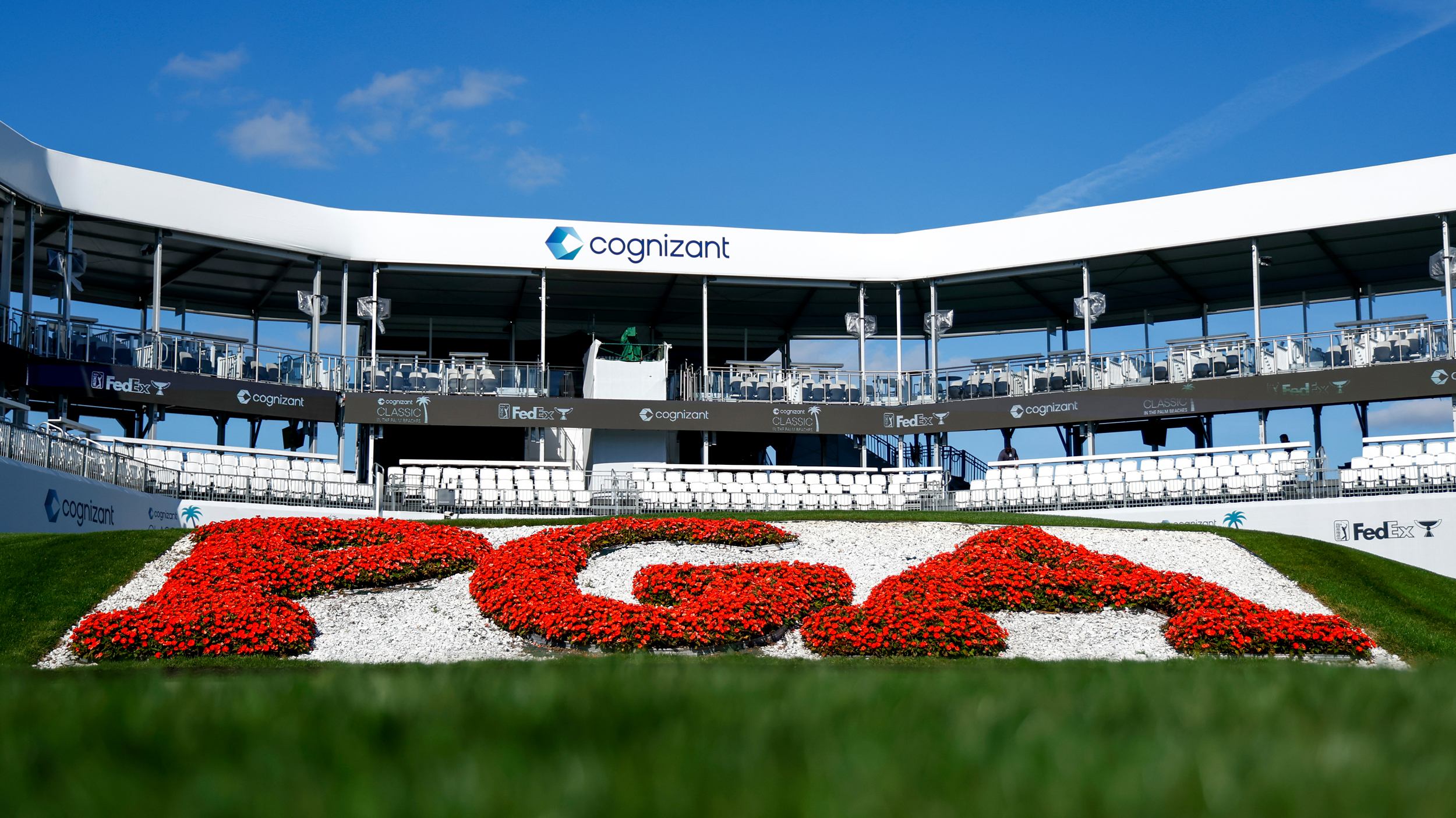 A PGA logo in red flowers in front of a Cognizant grandstand