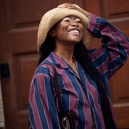 A guest wears, blue and red striped pants, a matching shirt, and beige hat, and white sneakers outside Baum und Pferdgarten during the Copenhagen Fashion Week Spring/Summer 2024 on August 9, 2023 in Copenhagen, Denmark. 