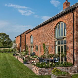 red brick wall villa with glass doors and windows garden and plants
