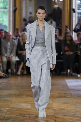 Victoria Beckham model wearing a gray suit with a gray top on the SS24 runway.