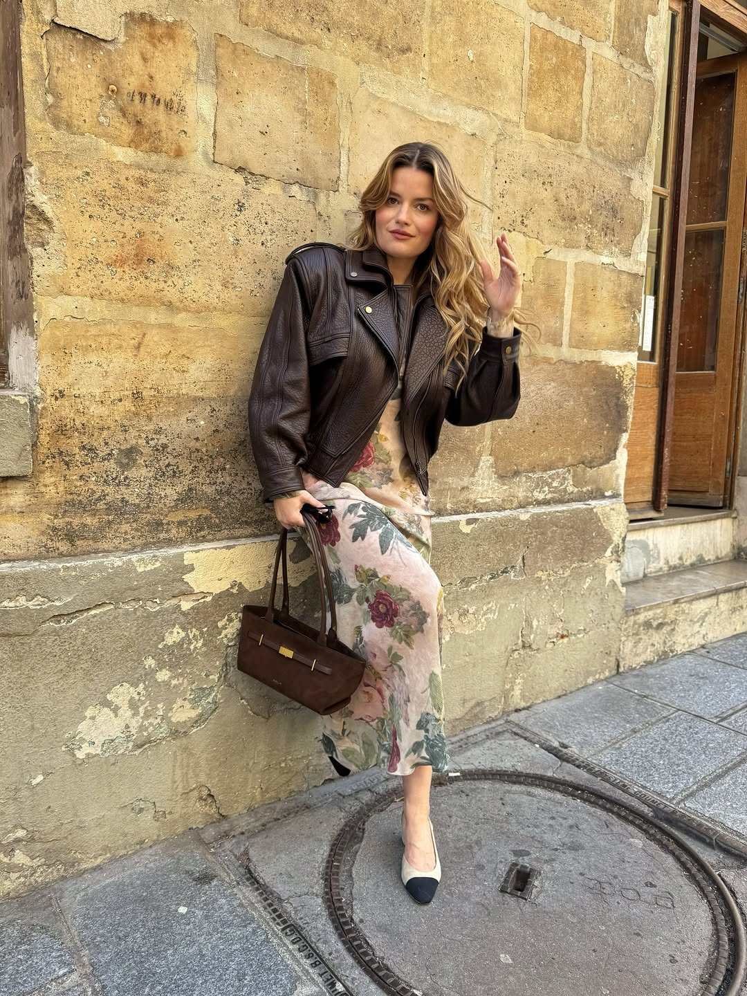 A woman wearing a floral slip dress and chocolate-brown leather jacket, part of Spring Basics Outfits 2026.