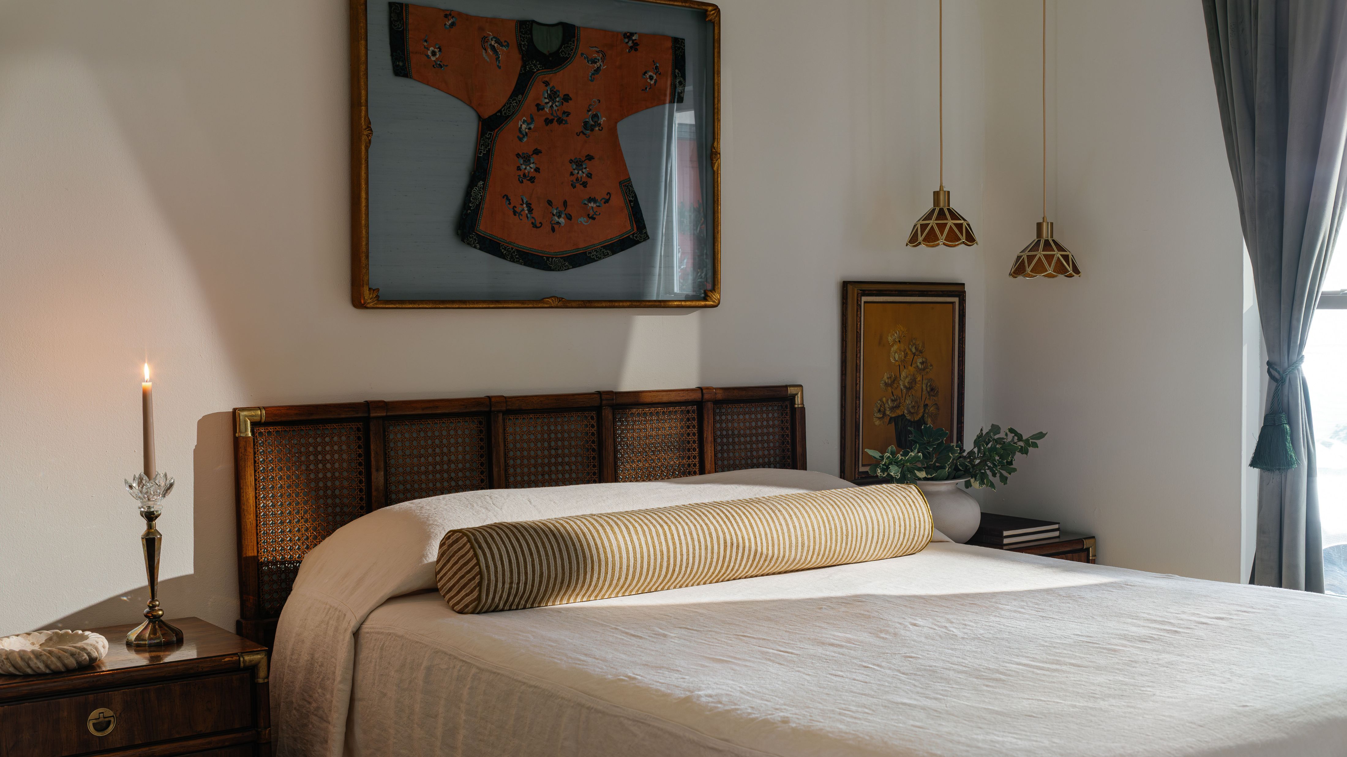 Serene bedroom featuring a bed with a cane headboard and single striped bolster pillow