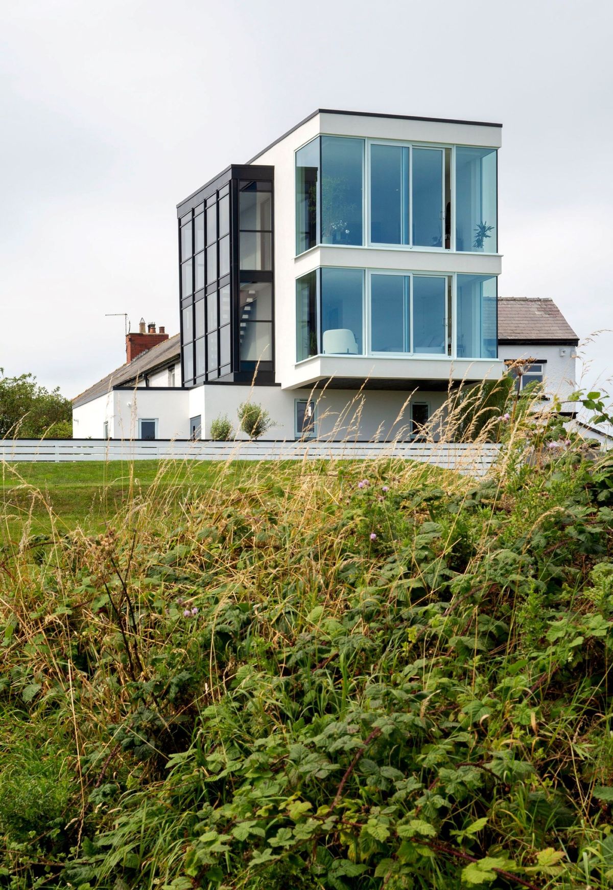 A white steel and glass box homes on a coastal plot