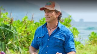Jeff Probst wears an orange hat and blue shirt while talking on Survivor.