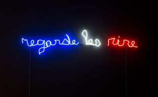 The street-level space consists of a three words, rendered in blue, white and red neon against a black wall