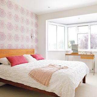white bedroom with pink cushions and table