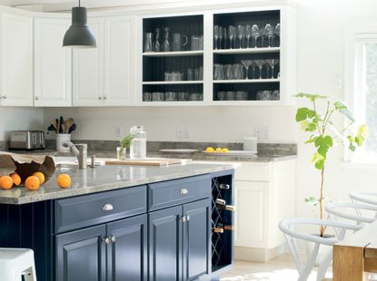 A kitchen painted a warm white shade with blue cabinets