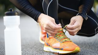 person lacing up a running shoe
