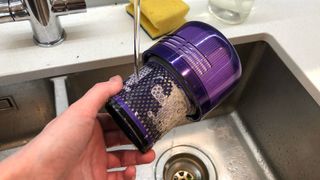 The filter of a Dyson vacuum cleaner being washed in a sink