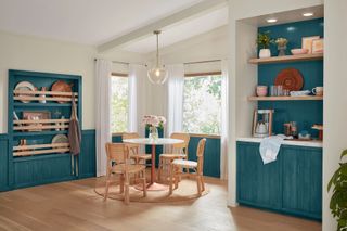 A kitchen with a small wooden dining table and blue stained wooden accents