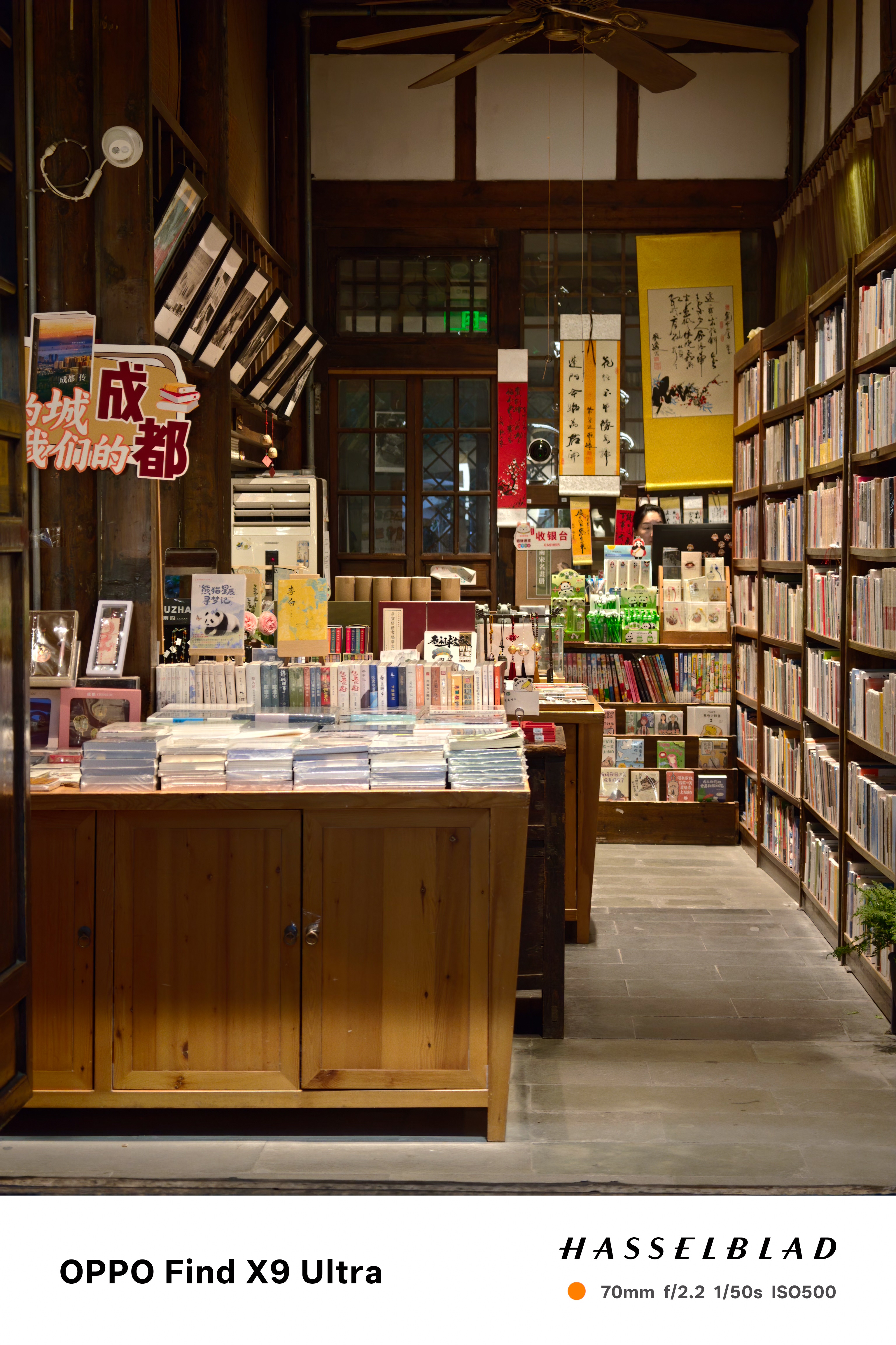 Warmly lit bookstore interior with wooden shelves, books, and hanging scrolls