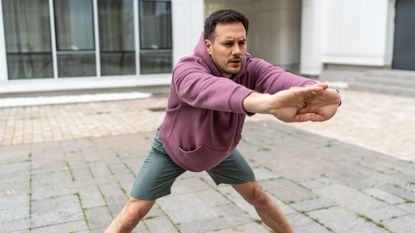Man in sportswear stretches his arms forward