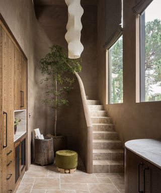 Earthy and organic staircase with neutral lime-colored walls, built-in wooden storage, large windows and houseplant