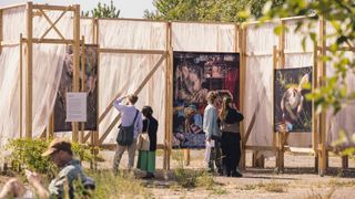 People looking a large photo prints on wooden frames outside