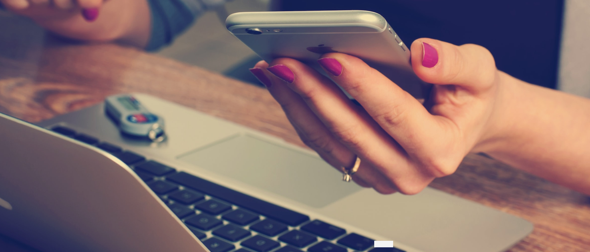 Woman on Macbook checking iPhone