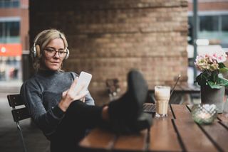Beste lydbok-app for norske bøker: En kvinne sitter ved et cafébord og hører på lydbok. (Foto: Getty Images)