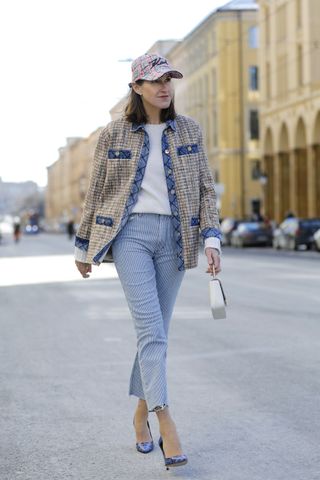 woman wearing tweed jacket, white t shirt, jeans, and baseball cap