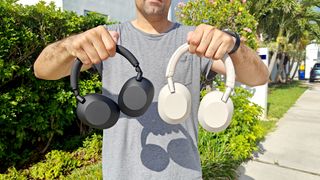 Our reviewer holding both the Sony WH-1000xM6 and Sony WH-1000xM5 headphones