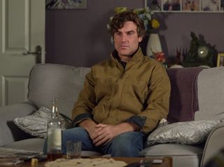 Theo Silverton sitting in the flat infront of a bottle of alcohol