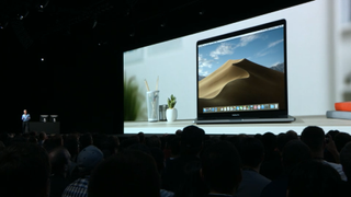Person presenting with image of Mac on big screen