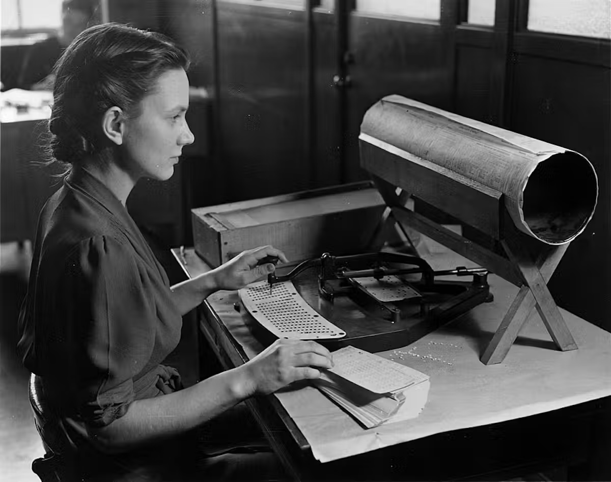 A black and white photo of a woman working at a punched card machine