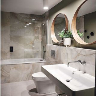 bathroom with beige porcelain tiles, white basin and circular mirrors