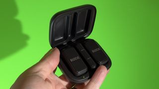 RØDE Wireless Micro case held in a hand in front of a green screen