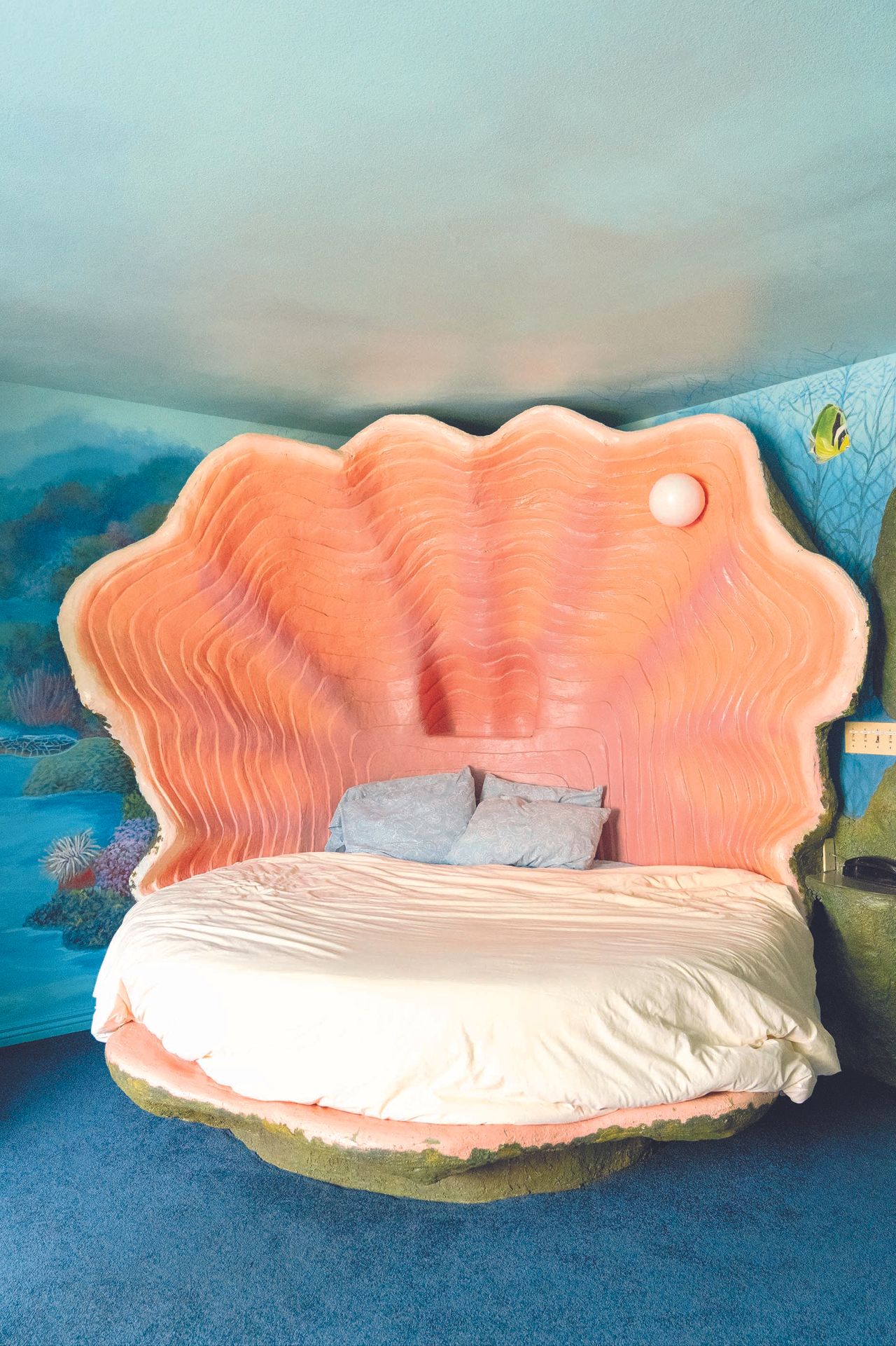 A shell-shaped bed sits in the center of a marine-themed hotle room.