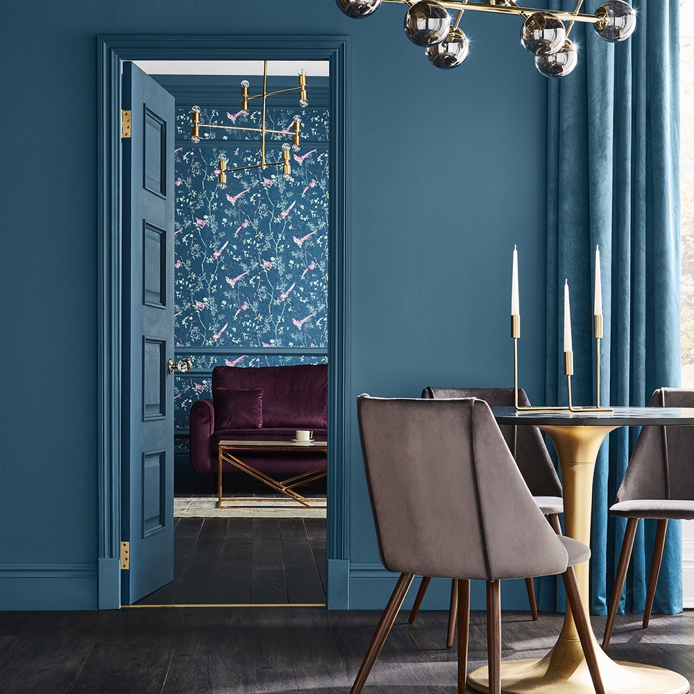 room with blue wall and wooden floor and round table with chairs and sofa