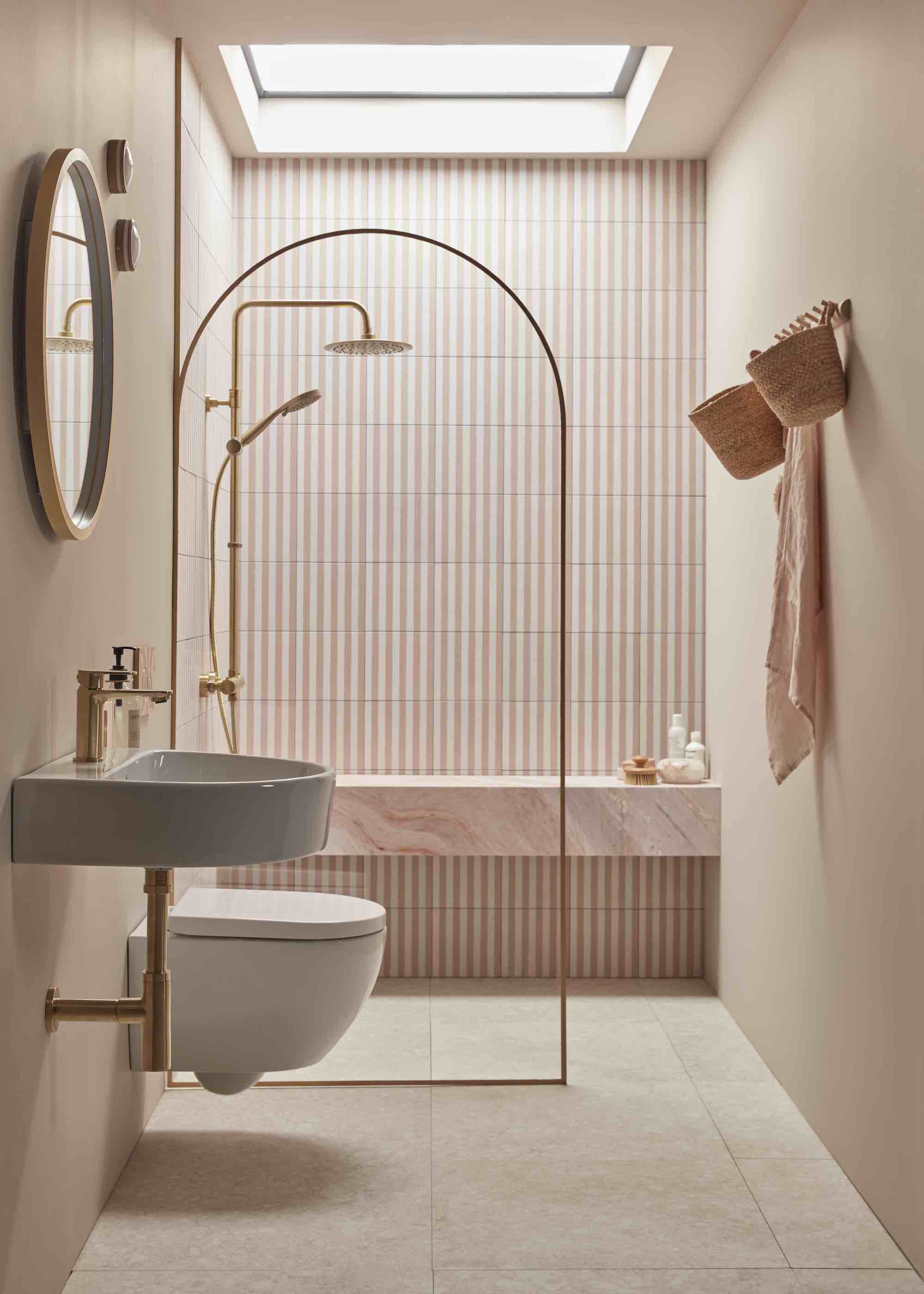 bathroom with arched shower screen and pink toned tiles from the floor up. There is also a toilet and and sink in the space.