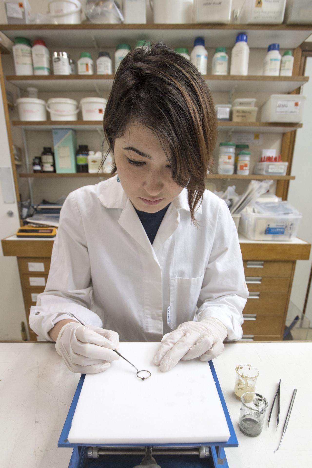 Lucie Altenburg, a conservator at MOLA, works on a 14th-century gold-plated ring with an oval cabochon setting, likely containing a garnet.