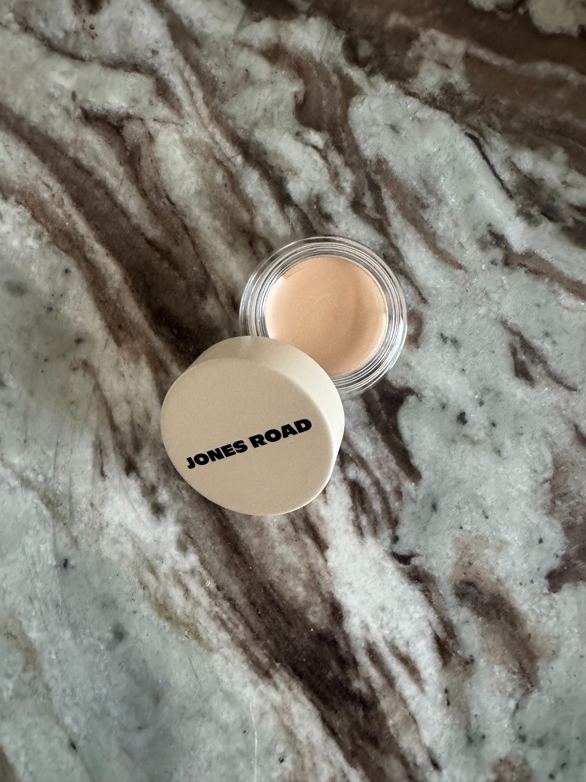 The jones road wide awake concealer on a marble table