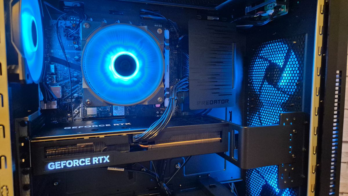 The inside of an Acer Predator Orion 5000 gaming PC sitting on top of a wooden surface in front of a white brick effect wall