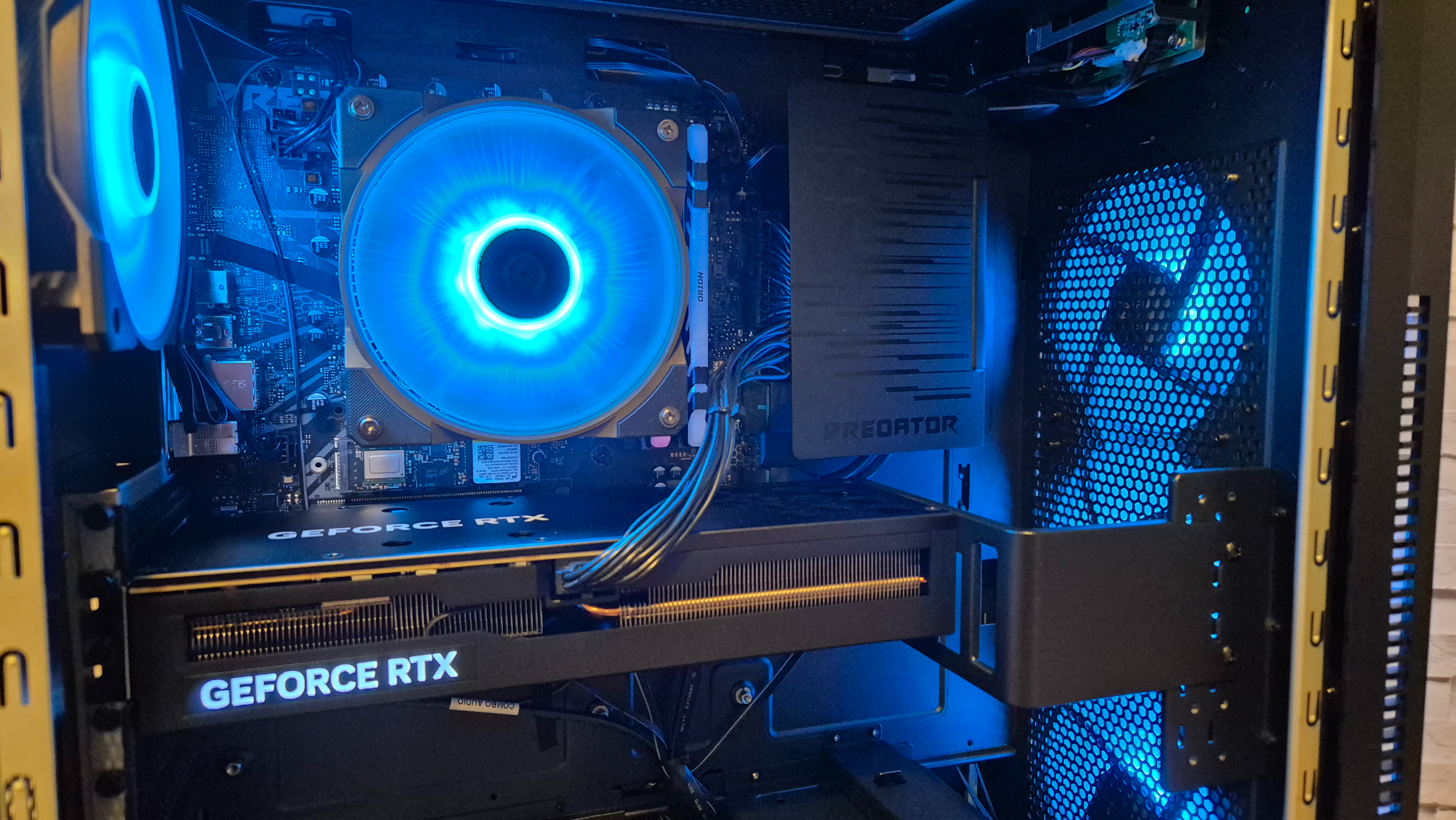 The inside of an Acer Predator Orion 5000 gaming PC sitting on top of a wooden surface infront of a white brick effect wall