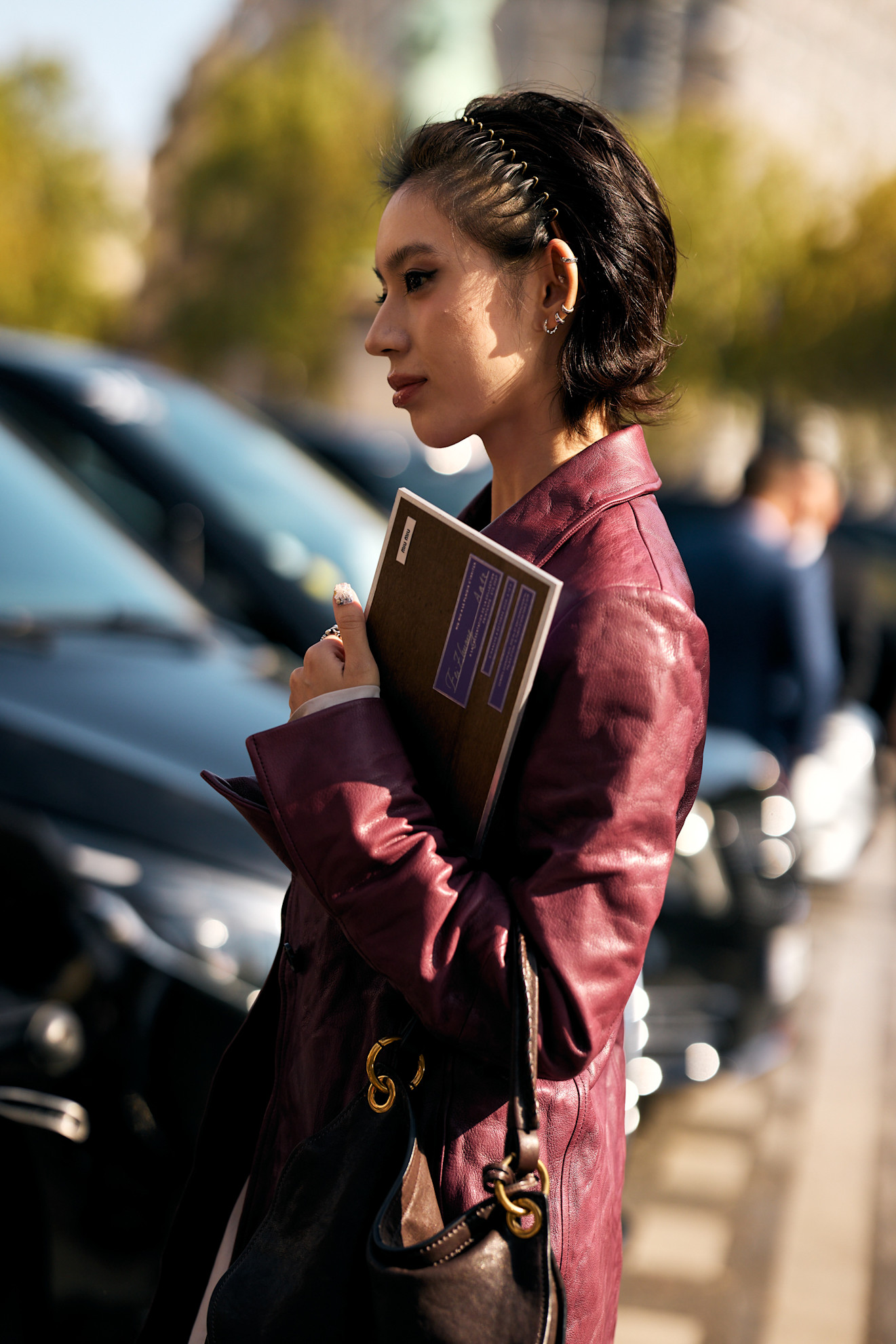a woman with short dark hair in a stretchy headband and burgundy leather blazer