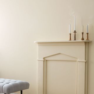 neutral wall with minimal fireplace and four long candles on the mantel