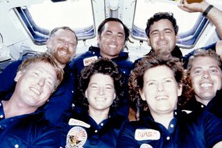 seven smiling people in blue flight suits pose on board nasa's space shuttle challenger