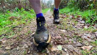 best trail shoes: Man wearing Salomon Genesis trail running shoes on the trail
