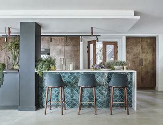 teal kitchen with tiles on side of kitchen island, teal bar stools, copper cabinetry, spotlights