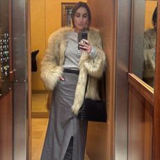 G&eacute;raldine wears a faux fur jacket with a henley shirt, gray skirt, and black leather boots.