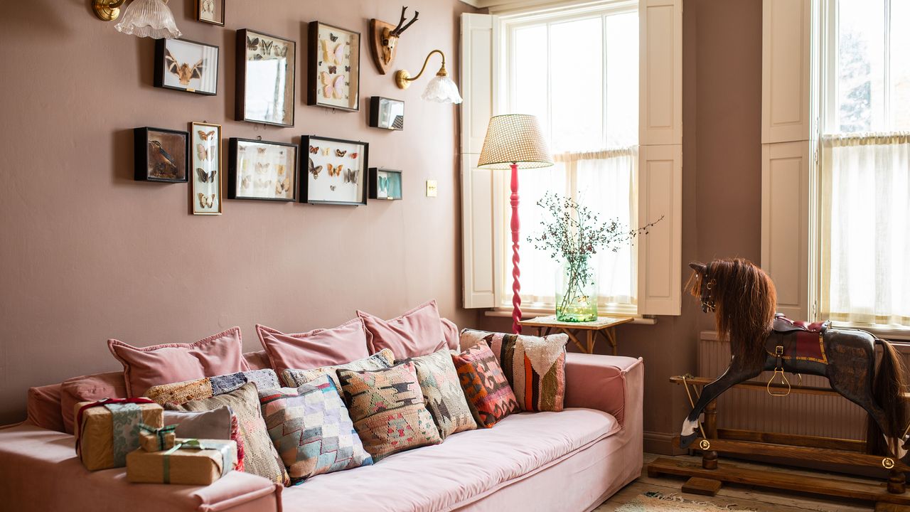 pink living room in victorian house with large sofa, rocking horse and window shutters