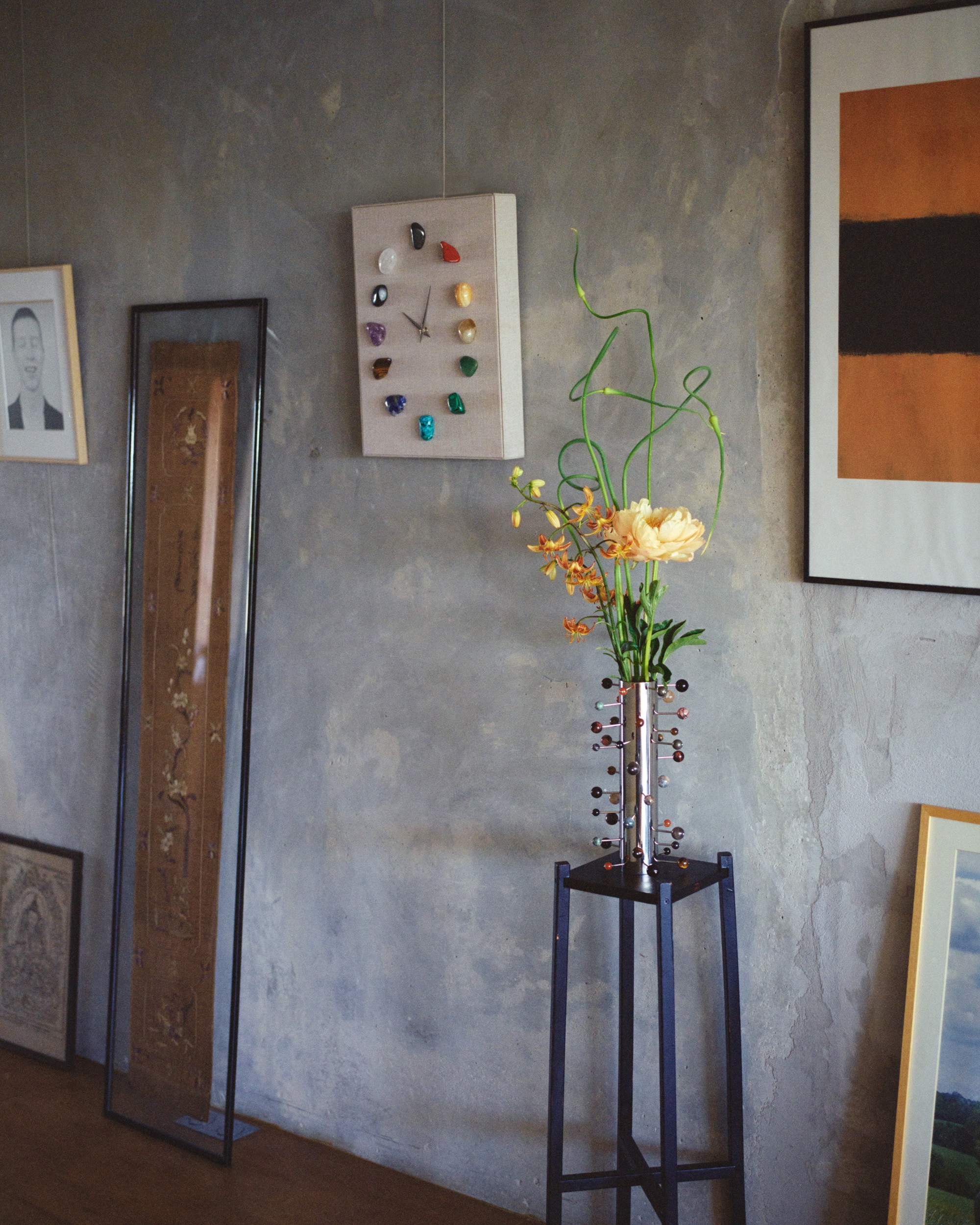 a gemstone clock on a grey limewash wall in an art gallery