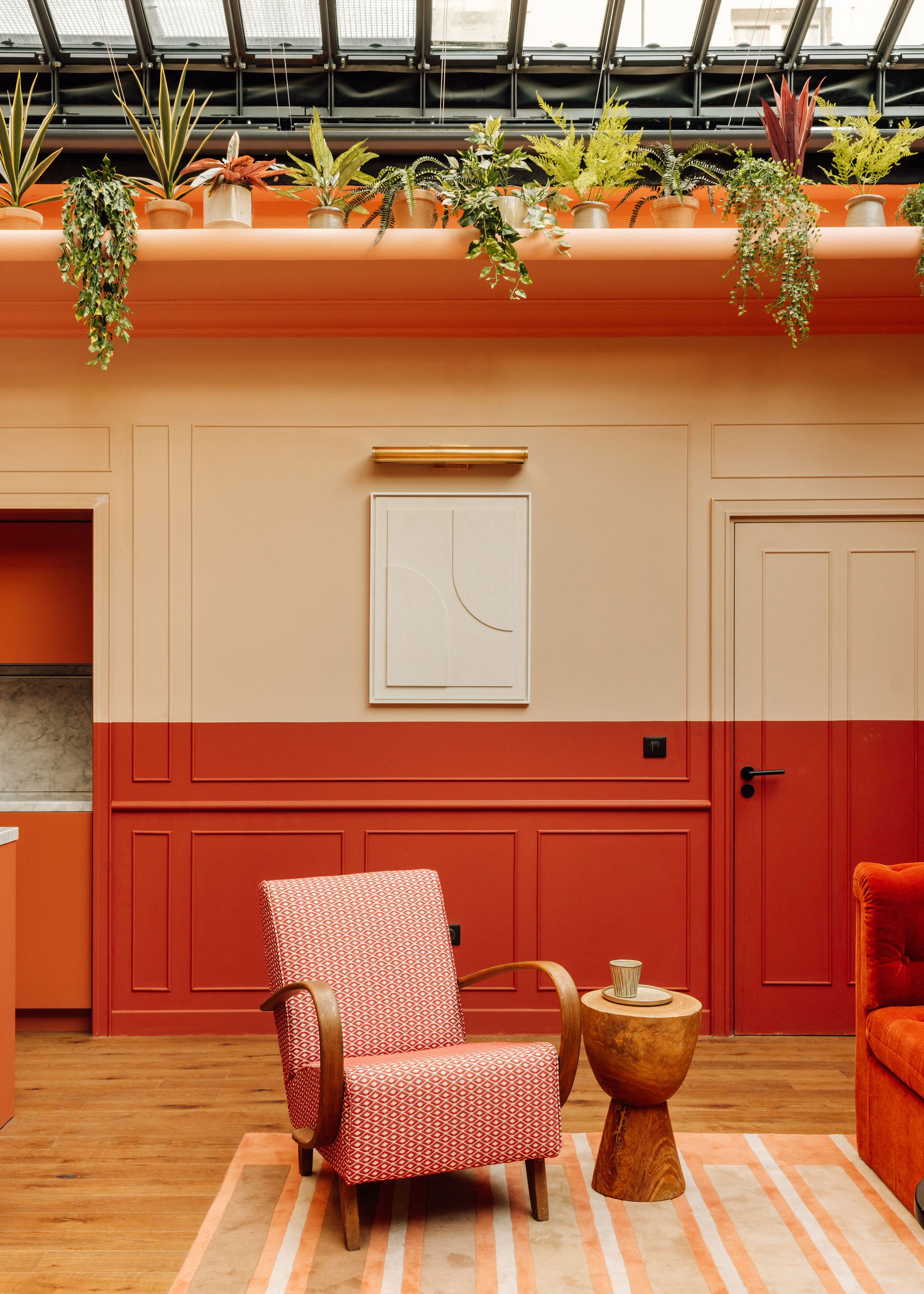 A vibrantly decorated hotel room boasts color-blocked walls n the tones of butter, orange, beige, and coral, sculptural furniture with a whimsical touch, and abstract artwork.