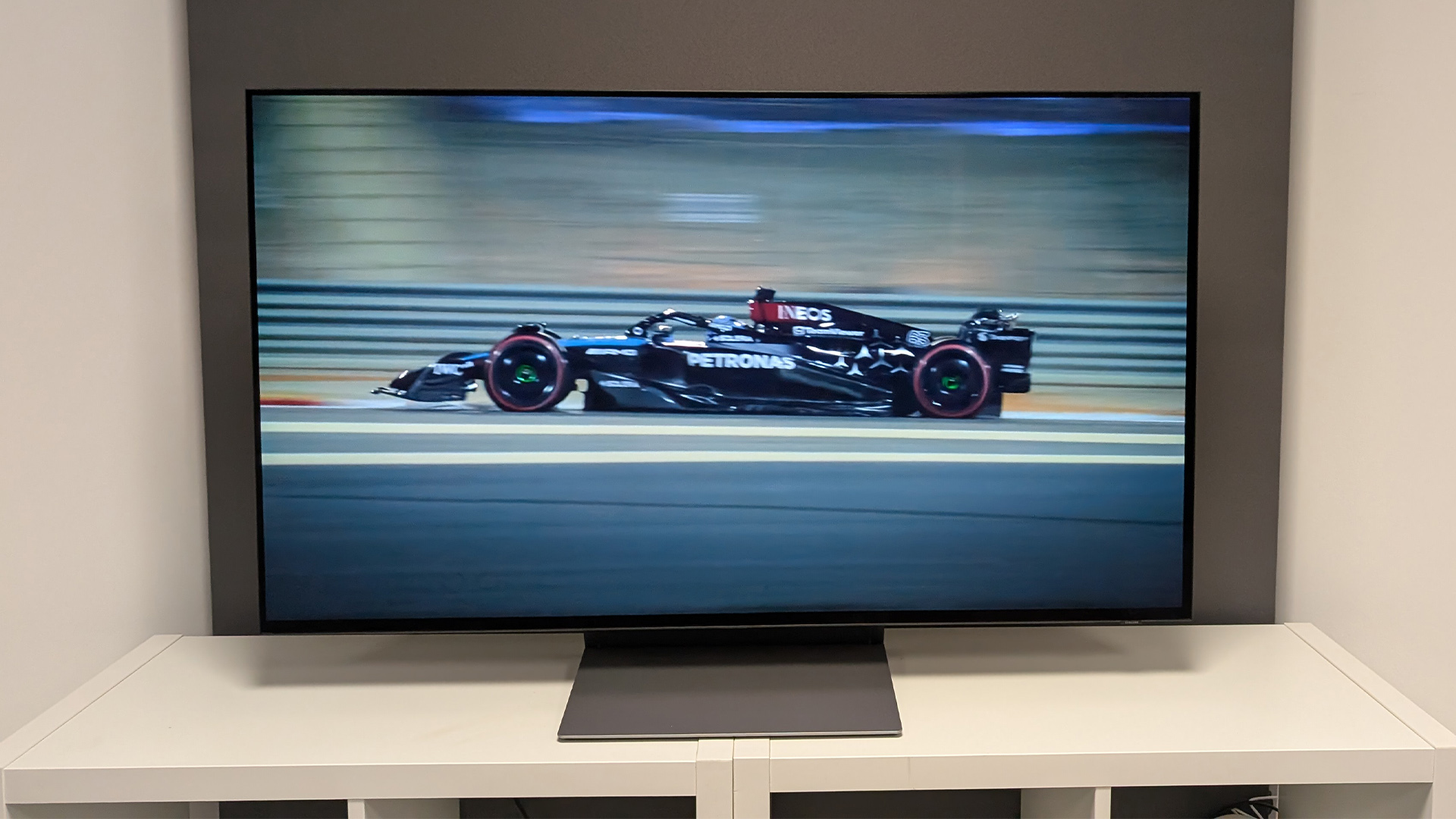 Samsung S90F 48-inch OLED TV on white wooden furniture, on screen is F1 car