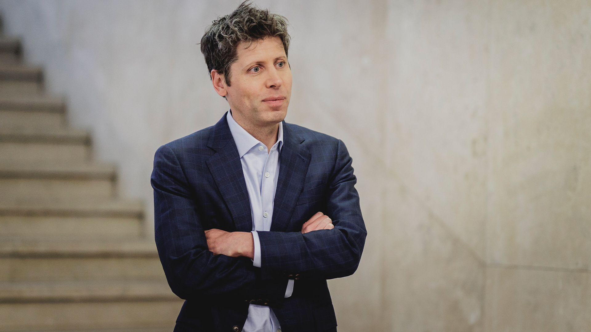 OpenAI CEO Sam Altman pictured in a suit with arms folded during an interview in Berlin, Germany.