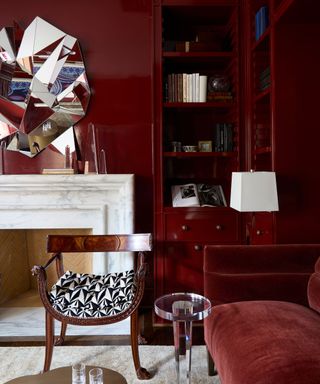 traditional dark red library room with white marble fireplace and built in shelving